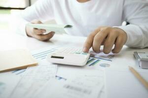 Business man Using calculator analyzing investment chart on the desk working at office. photo