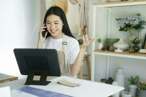 Young asian businessowner sitting Ceramic product sales room working on laptop. photo