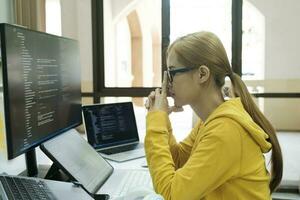 Young woman covering her face with both hands with the stress of work coding and programming software. photo