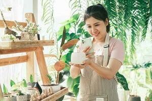 sonriente joven mujer tomando teléfono inteligente imagen de planta en un pequeño tienda foto