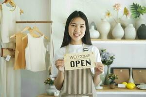 joven asiático negocio propietario torneado abierto firmar producto Tienda y Listo a Servicio para Bienvenido el cliente. foto