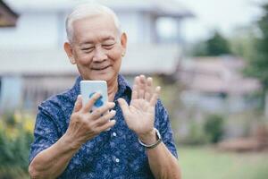 Happy asian elder man using smartphone. photo