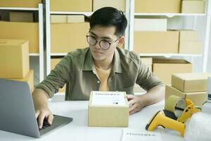 Young man checking parcel address using laptop. photo