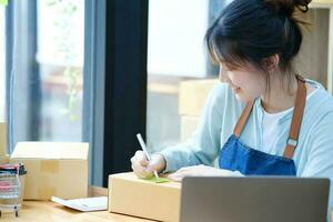 Online small business owner writing address on parcel box. photo