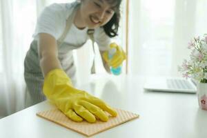 joven mujer limpieza mesa vistiendo guantes a hogar. foto