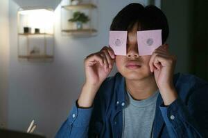 Exhausted tired workaholic young man with painted eyes on stickers photo