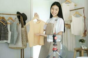 Young asian businesswoman fashion blogger showing cloth with smiling face. photo