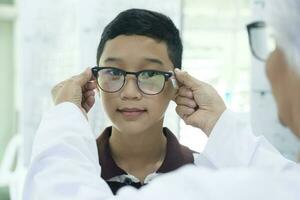 Smart young boy trying out new eyeglasses. photo