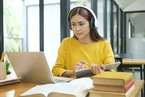 Woman learning online using laptop and writing notes. photo