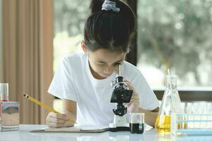 Little child with learning class in school laboratory using microscope photo