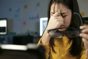 Young woman overtime work and feel eye tire. photo