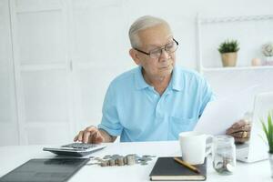 Serious man sitting at table near utility bill and calculating expenses photo