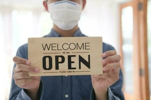 Young business owner wear face mask and opening sign. photo