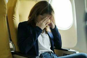 Businesswoman In a plane, covering her face with both hands with the stress. photo