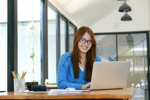 A female college student uses a computer to access the Internet for online learning. photo