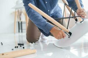 Young man doing DIY work, assembling furniture at home. photo