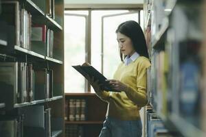 estudiante en pie y leyendo libro a biblioteca. foto