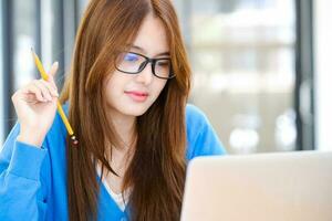 Young female college student uses a computer to access the Internet for online learning. photo