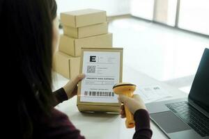 Female online business owner scan shipping label on parcel. photo