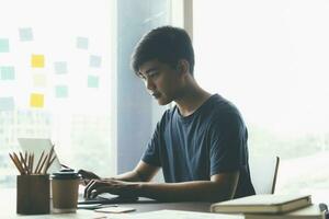 Young collage student using computer and mobile device studying online. photo