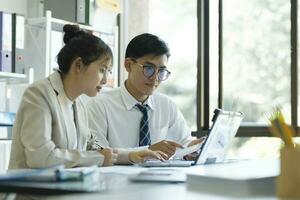 Businesspeople are working by discuss and analyses their project by using laptop and graphs. photo