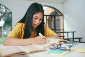 Serious Asian female student reading books for exam preparation photo