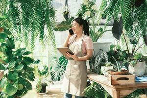 joven mujer planta tienda propietario es comprobación cliente orden desde sitio web foto