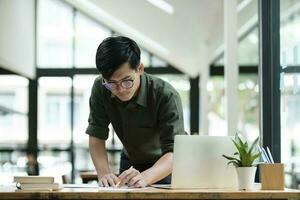 joven asiático negocio hombre o estudiante trabajando en línea en computadora ordenador portátil. foto