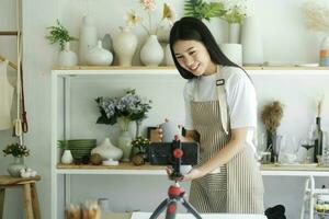 Young asian businesswoman fashion blogger showing ceramic products with smiling face. photo