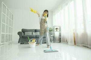 joven mujer teniendo divertido mientras limpieza a hogar. foto