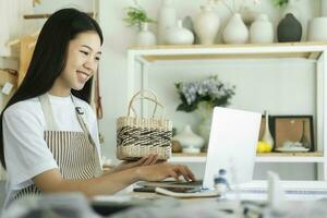joven asiático mujer de negocios Moda blogger demostración tejido cesta productos con sonriente rostro. foto