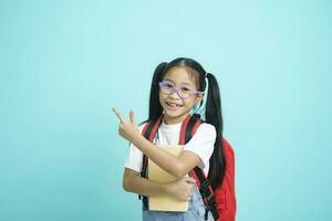 Smiling little girl in glasses pointing finger upward. photo