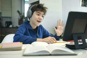 Young boy using computer and mobile device studying online. photo
