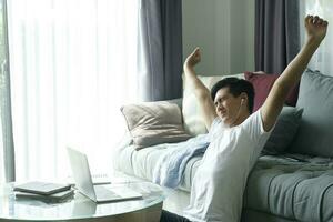 Young businessman sitting at home working at his desk hands up and stretching his arms. photo