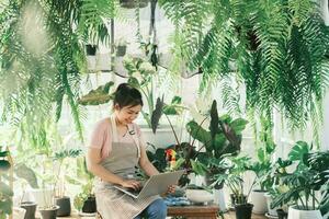 Young  woman plant shop owner is checking customer order from website photo