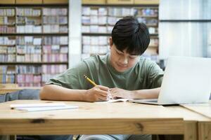 Young collage student using computer and mobile device studying online. photo