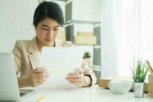 Young asian female freelan sit reading report on paper in online clothing store. photo