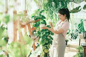 Smiling young woman taking smartphone picture of plant in a small shop photo