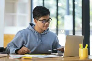 Young collage student using computer and mobile device studying online. photo