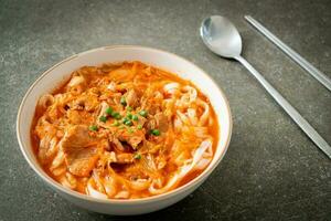 Korean udon ramen noodles with pork in kimchi soup photo