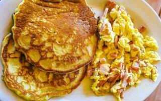 Breakfast scrambled eggs with pancake pancakes nicely arranged on plate. photo