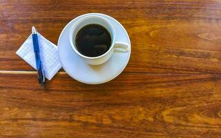 Cup of americano black coffee with notepad and pen Mexico. photo