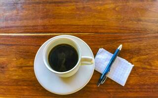 Cup of americano black coffee with notepad and pen Mexico. photo