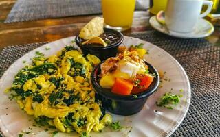 Breakfast scrambled eggs spinach fruit potatoes nicely arranged on plate. photo