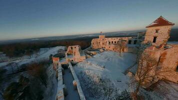 antenn se av skön historisk slott ruiner på de kulle i vinter- på solnedgång. tenczyn slott, polen. filmad på fpv video