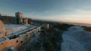 antenn se av skön historisk slott ruiner på de kulle i vinter- på solnedgång. tenczyn slott i rudno, polen. filmad på fpv Drönare video