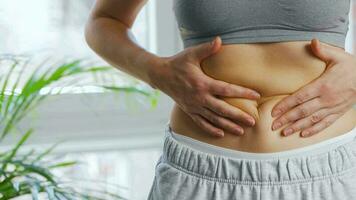 Woman compressing the skin on her stomach checking for cellulite and excess subcutaneous fat video