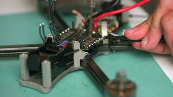 homme soudures le fils tandis que assemblage le drone. construction et restauration de fpv drone video