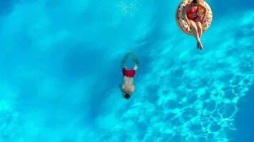 couple ayant amusement dans le piscine, le homme plongées et le femme mensonges sur une Donut video