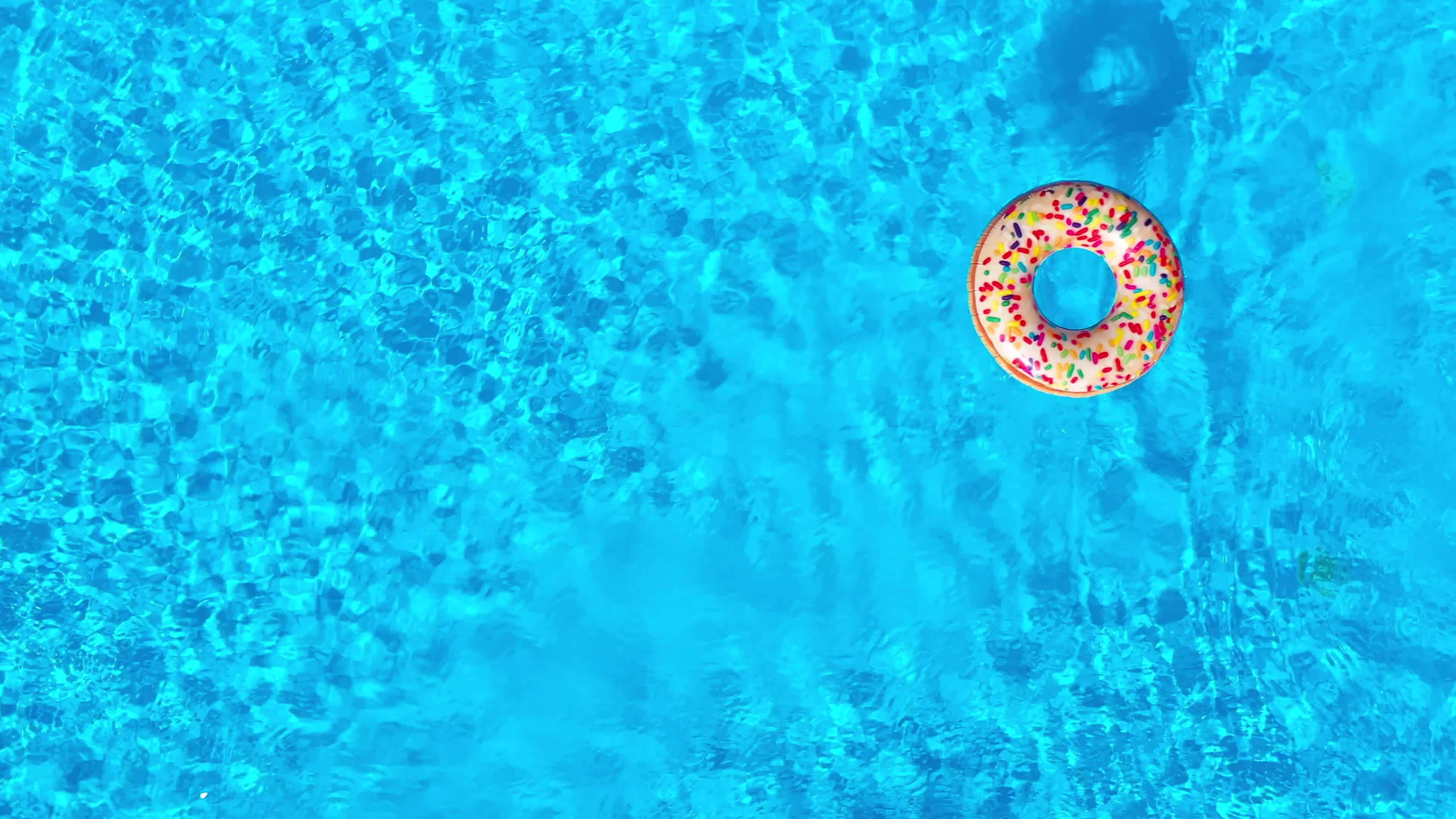 Top down view as a man dives into the pool and swims with inflatable ...